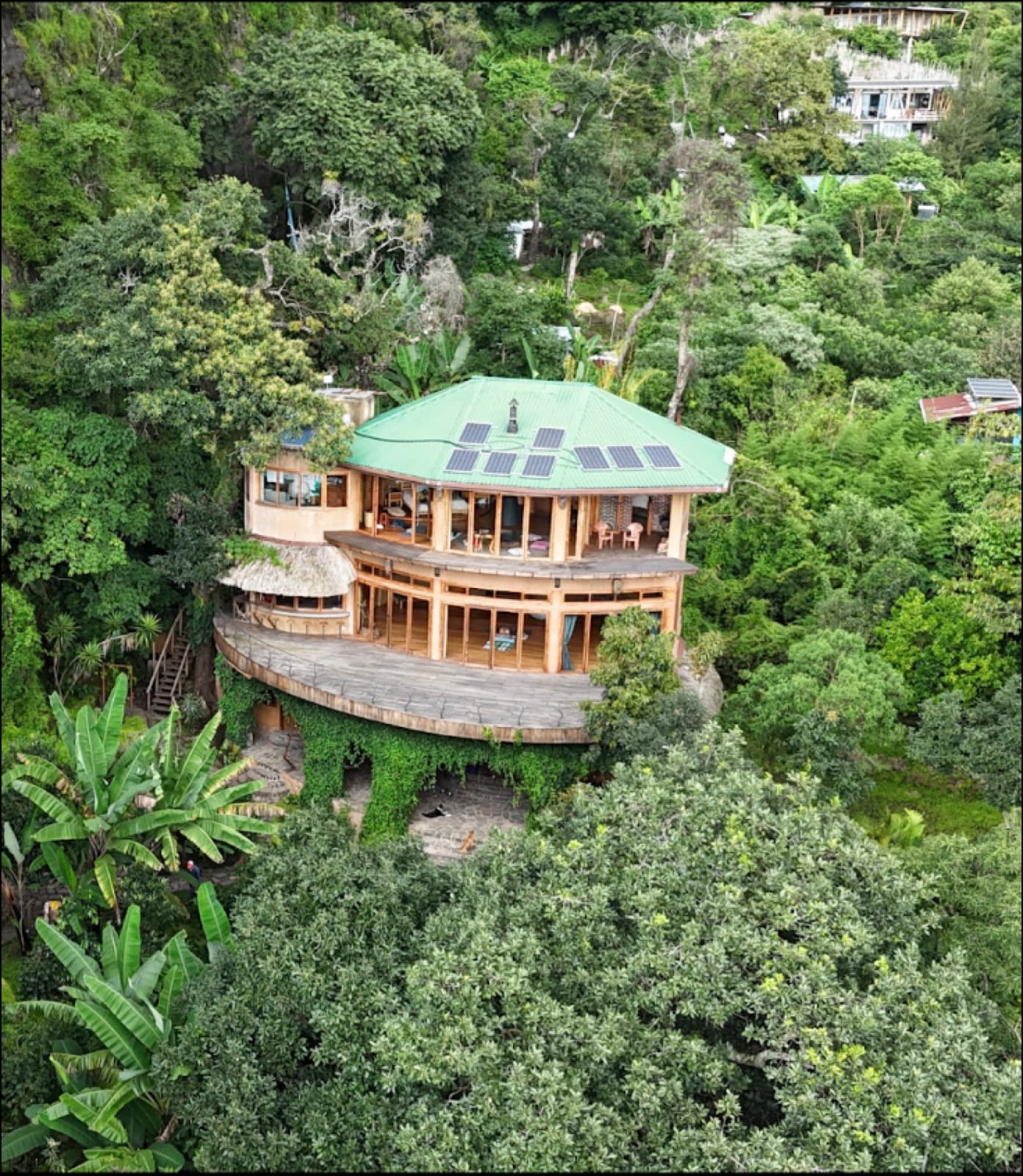 The round solar-roofed lodge set into the forest canopy